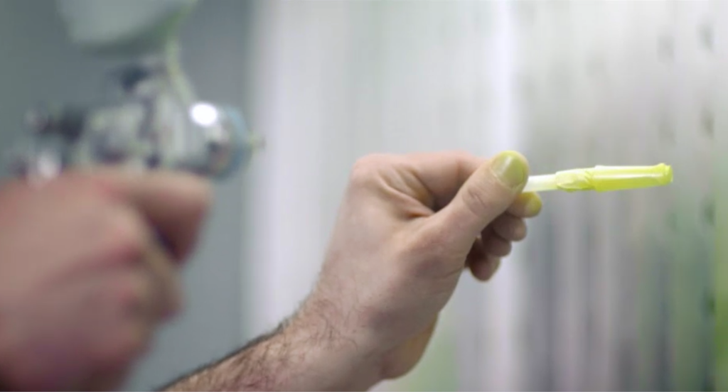 An engineer sprays a prototype pen by hand